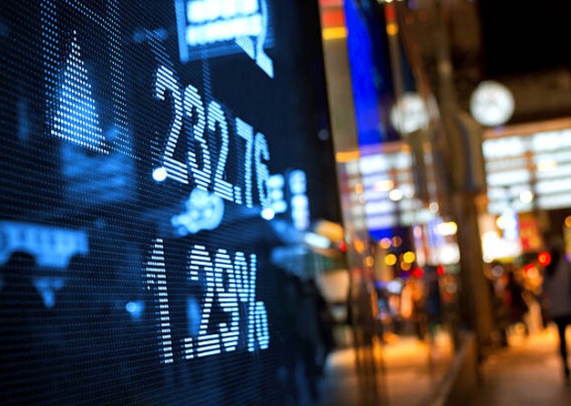 A digital ticker board displaying real-time stock market data at night.